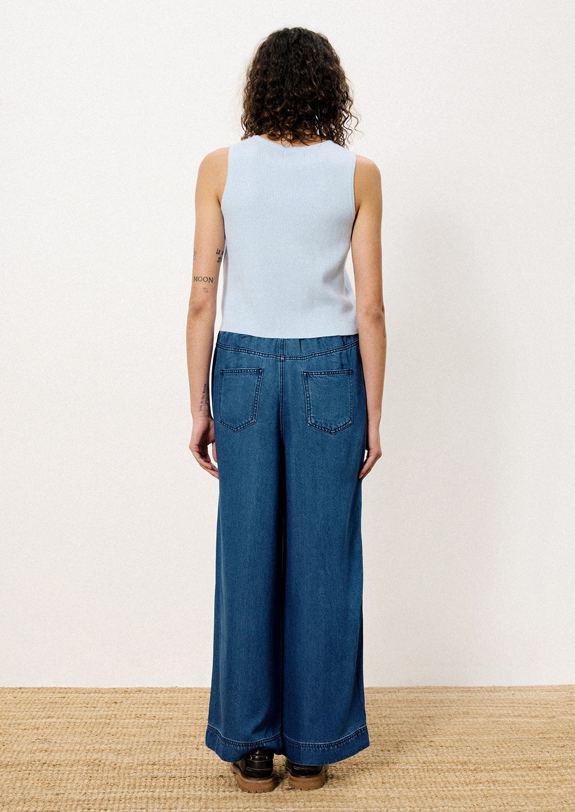 A person wearing a pair of relaxed denim pants with elasticized waistband.