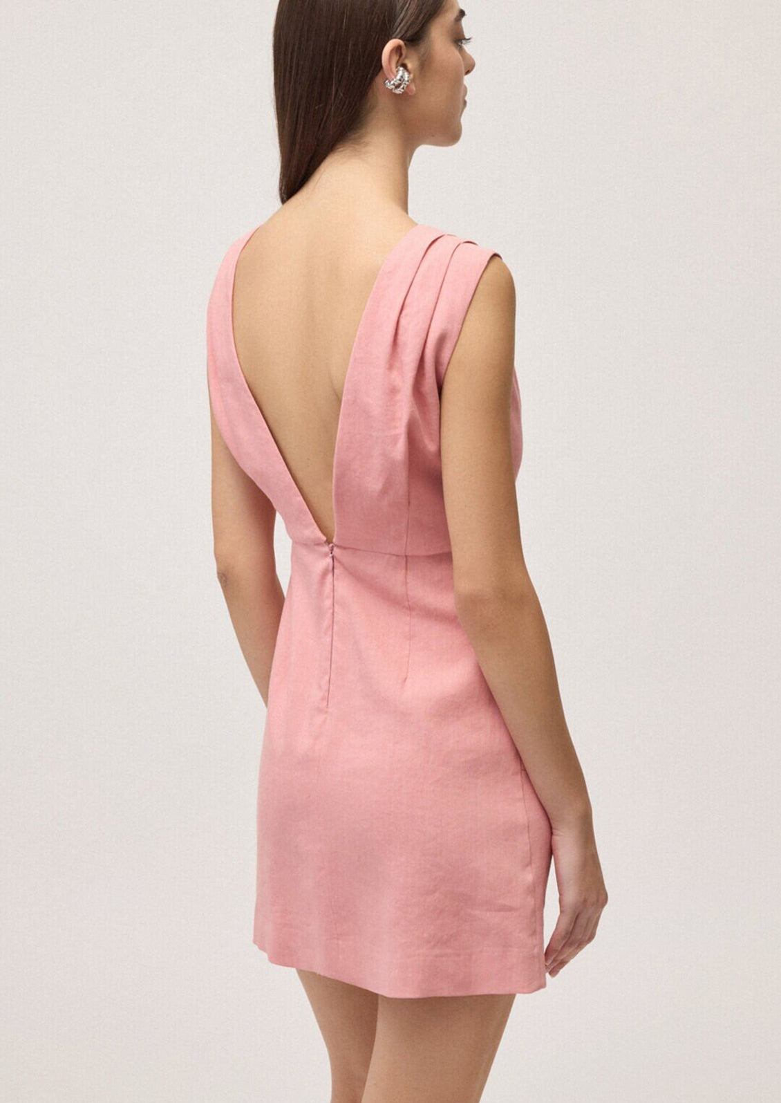 Pink dress with open back worn by a model on a light gray background