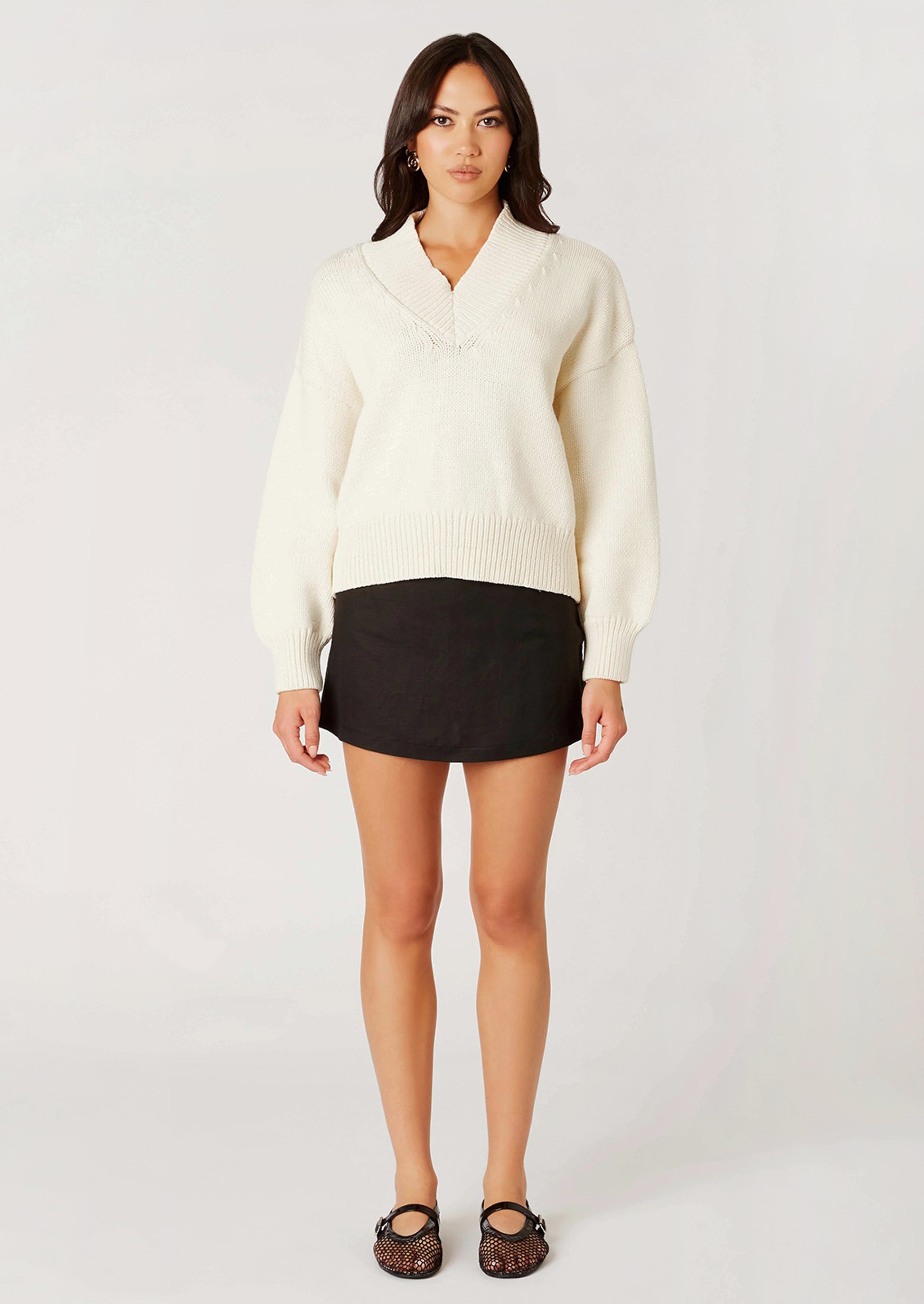 Woman wearing a cream sweater against a white background