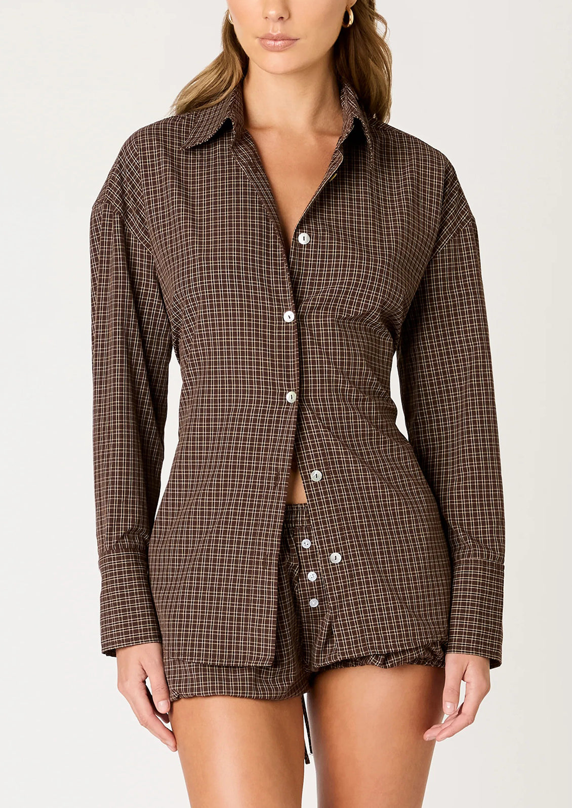A person wearing a brown plaid button down shirt.