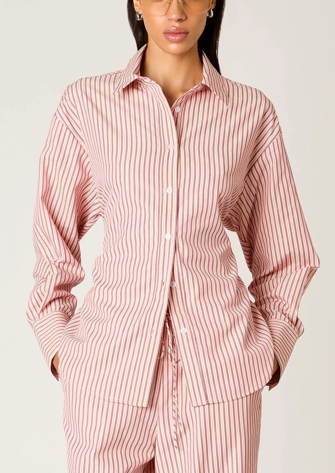 Person wearing a pink and white striped pajama set against a plain background