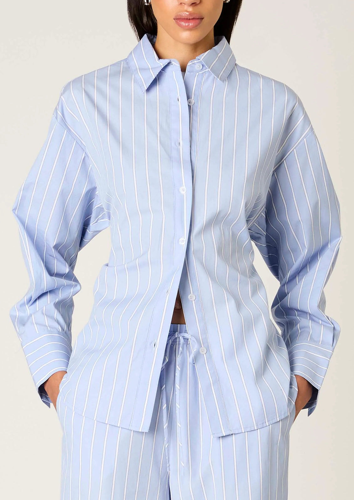 Person wearing a light blue striped shirt and pants on a plain background