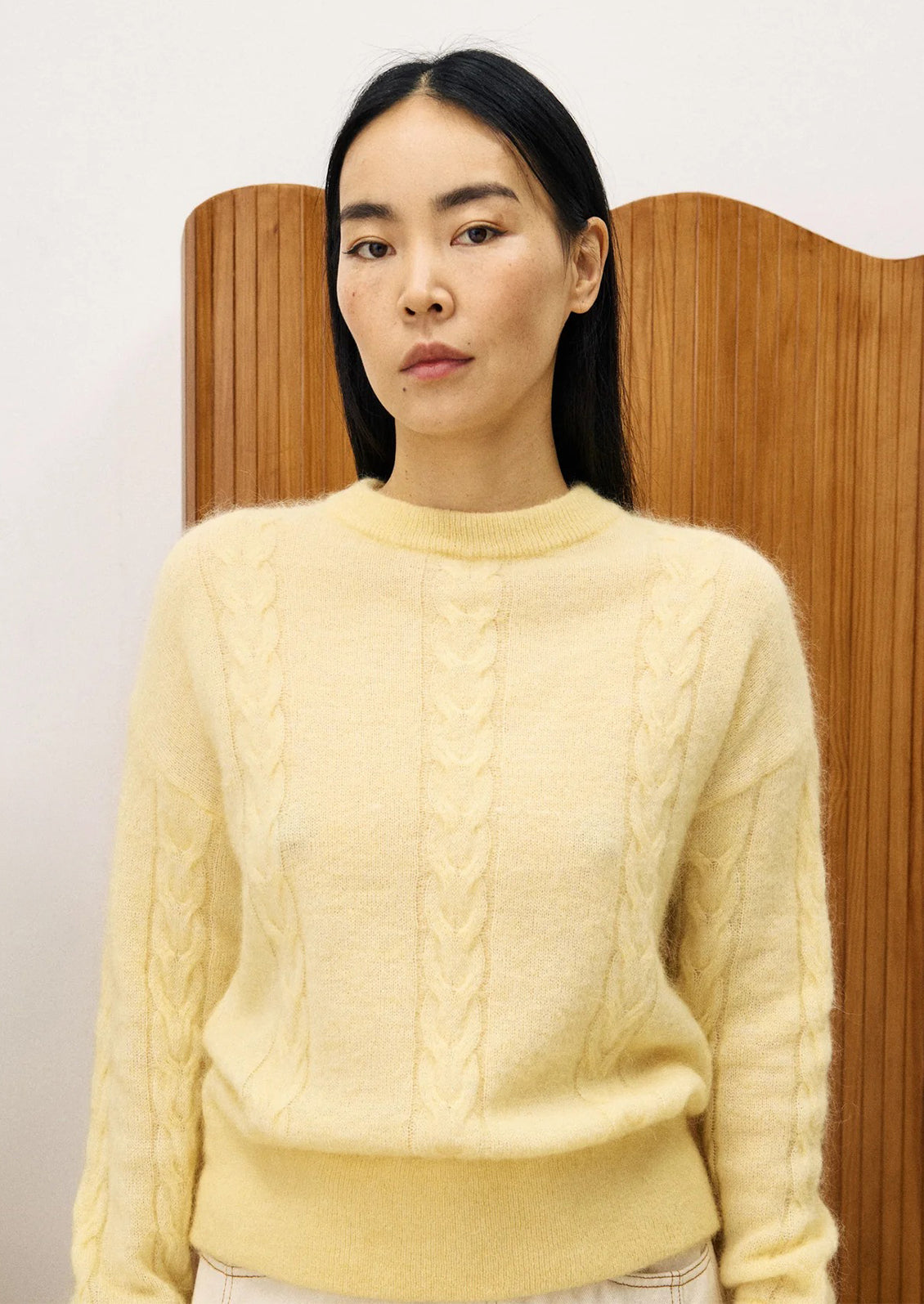 Woman wearing a light yellow cable knit sweater.
