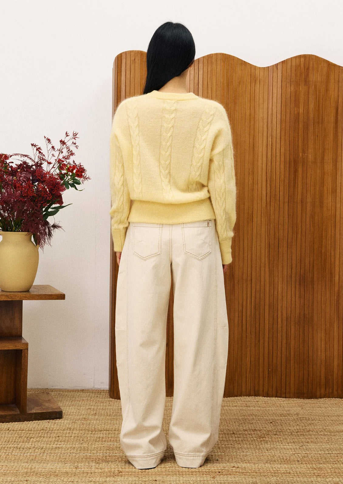 Woman wearing a light yellow cable knit sweater.