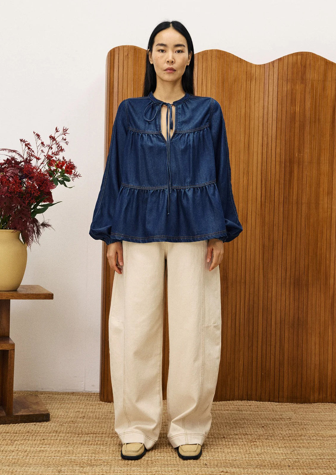 A woman wearing a denim top with shirred ruching.