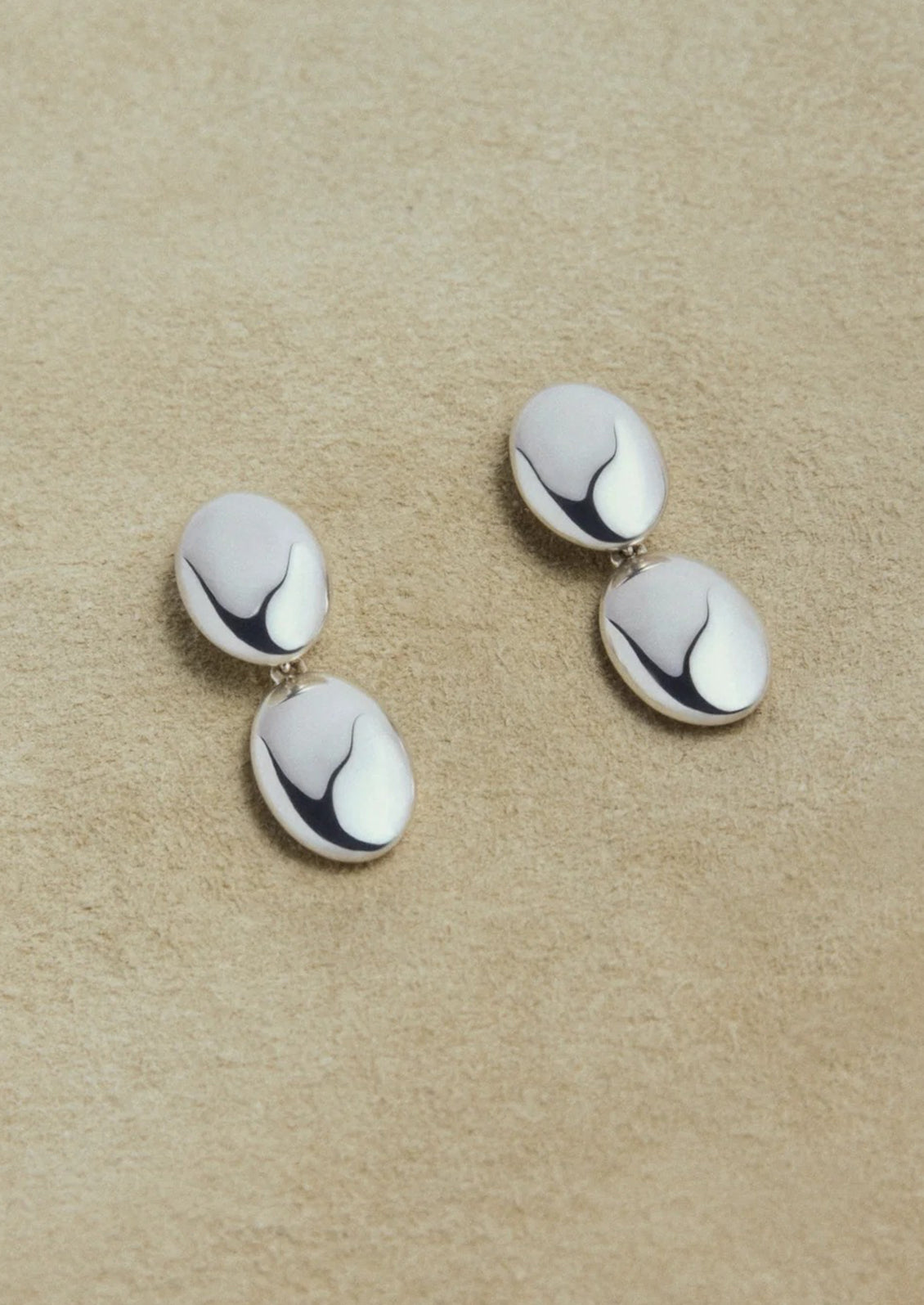 Pair of silver earrings on a beige background