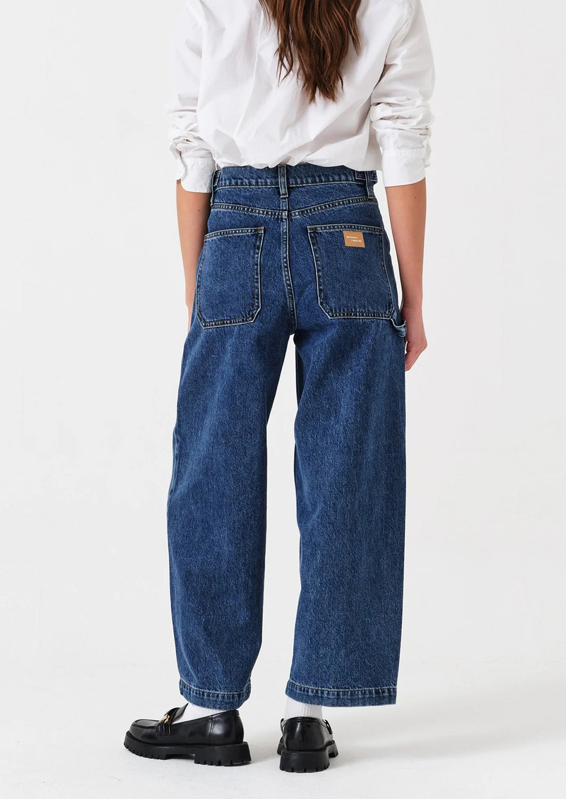 Person wearing blue jeans and a white sweatshirt on a white background