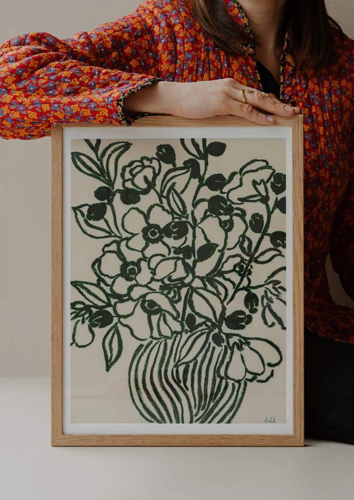 Person holding a framed black and white floral print against a neutral background
