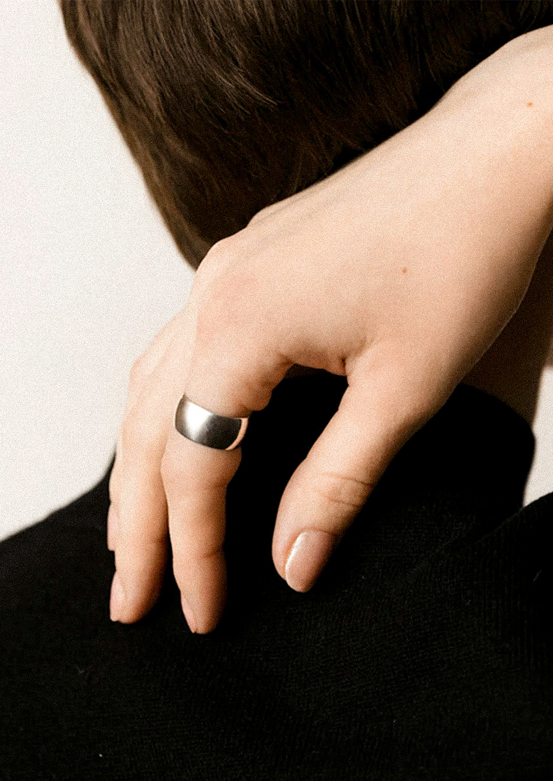 Close-up of a hand wearing a silver ring on a plain background