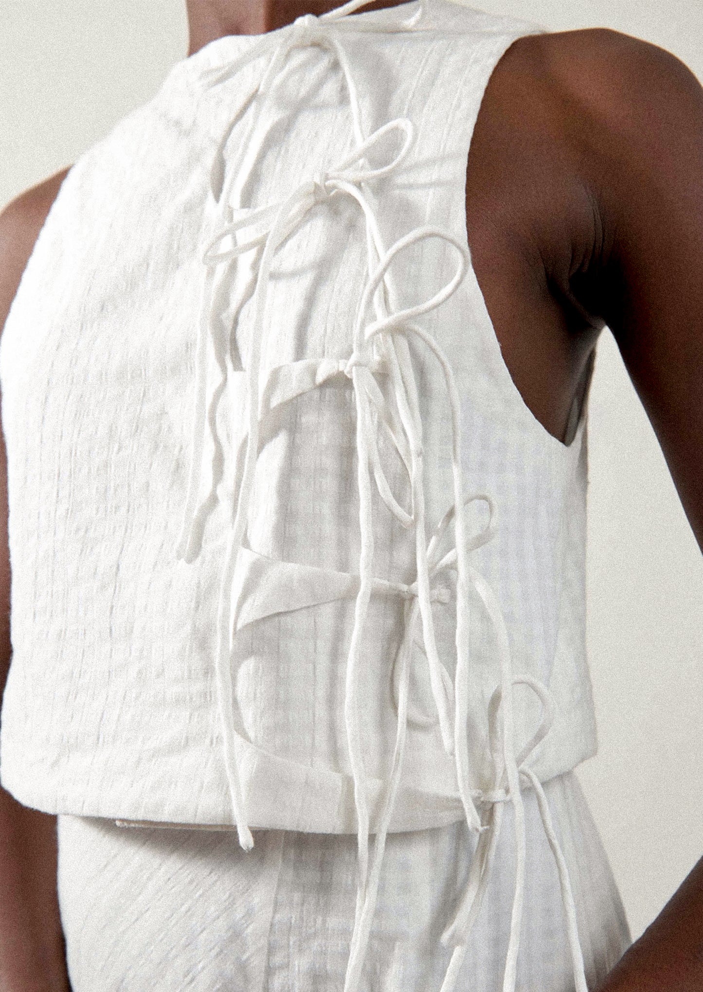 A woman wearing a tie front blouse in white tonal gingham fabric.