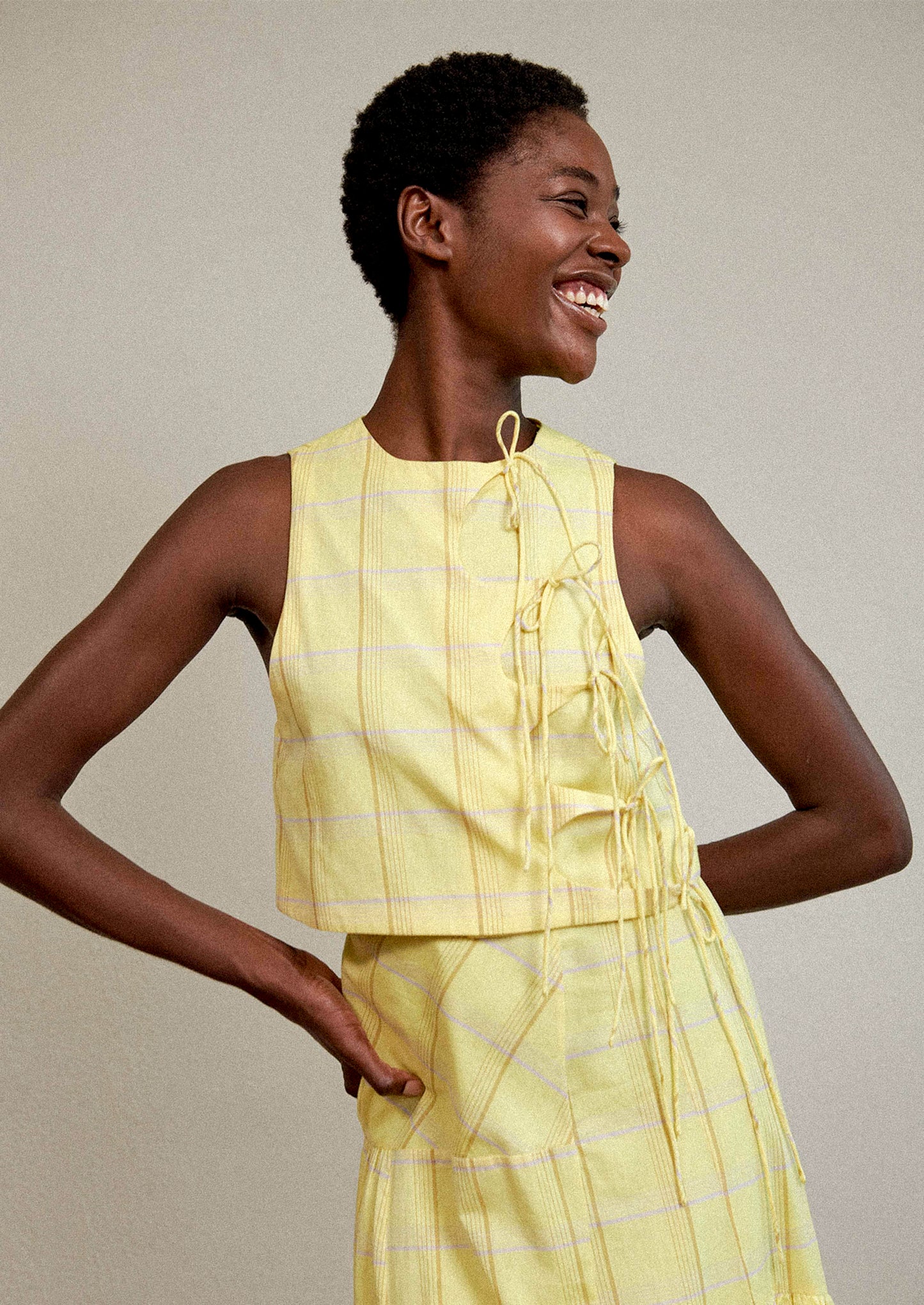 A woman wearing a tie front blouse in yellow plaid fabric.