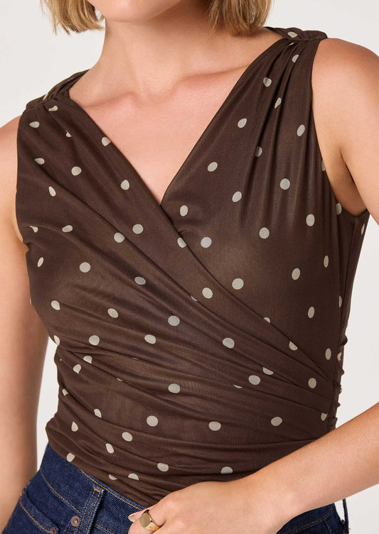 A person wearing a bodysuit in brown with cream polka dots.
