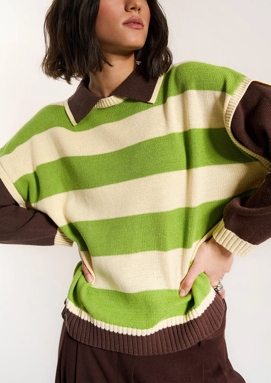 Person wearing a green and brown striped sweater with a plain background