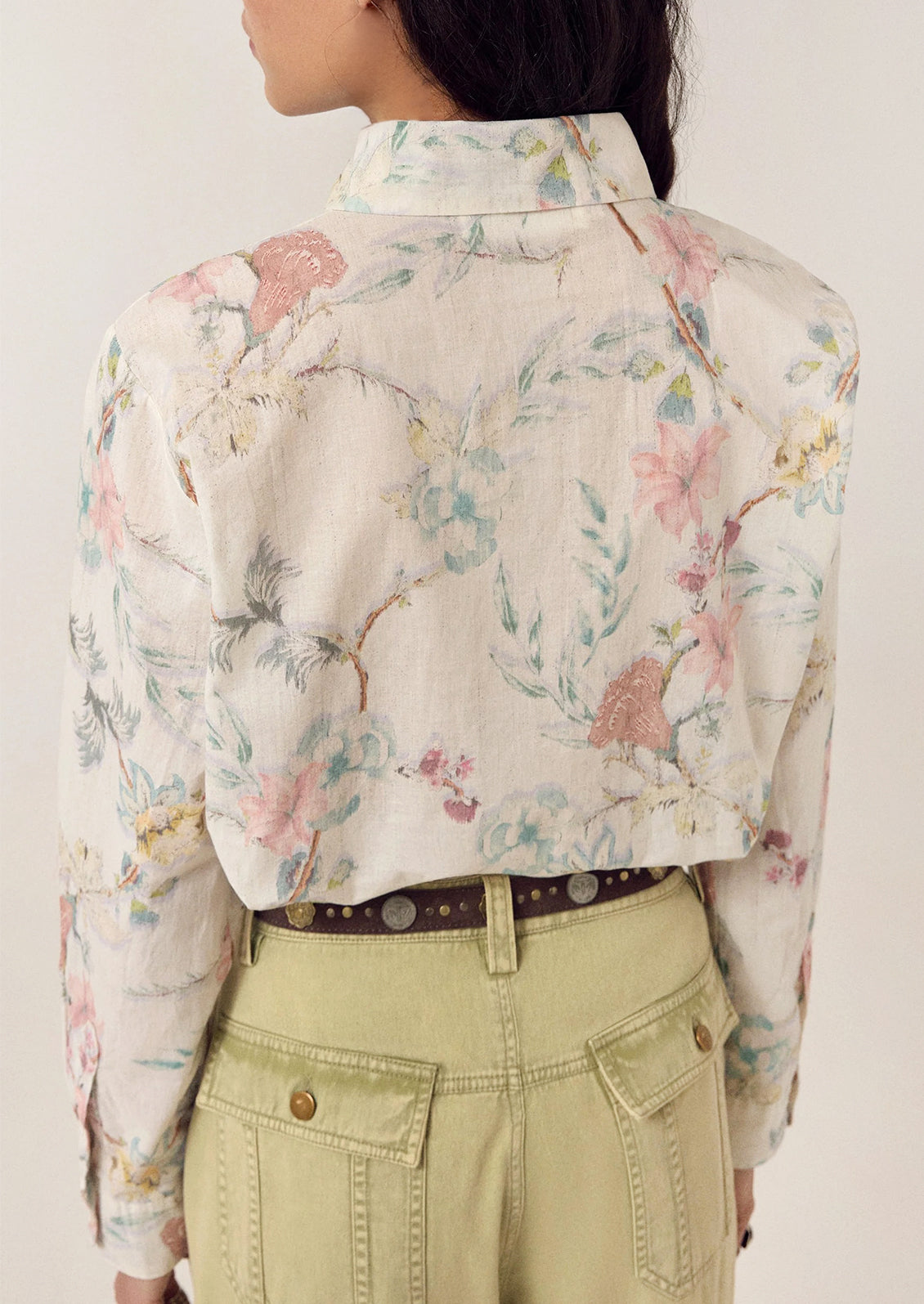 A person wearing a white floral print button front shirt.