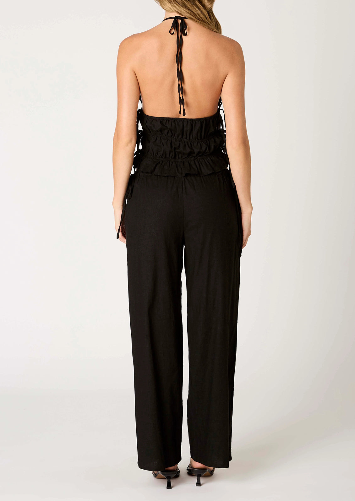 A person wearing a pair of relaxed black wide leg trousers with side tie detail at waist.