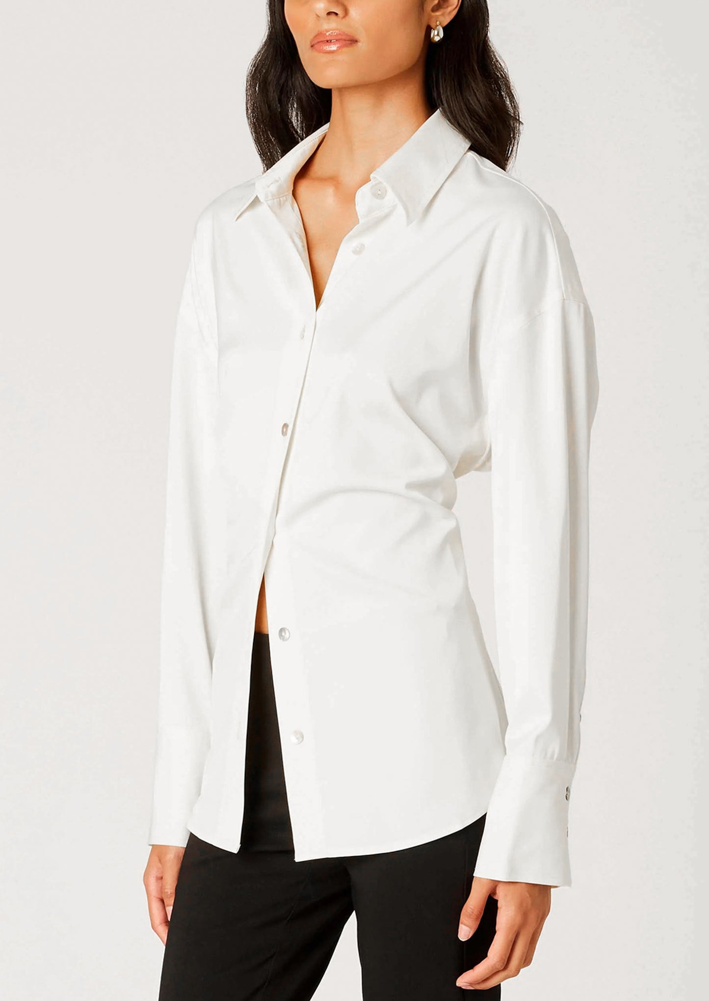 Woman wearing a white button-up shirt and black pants on a plain background