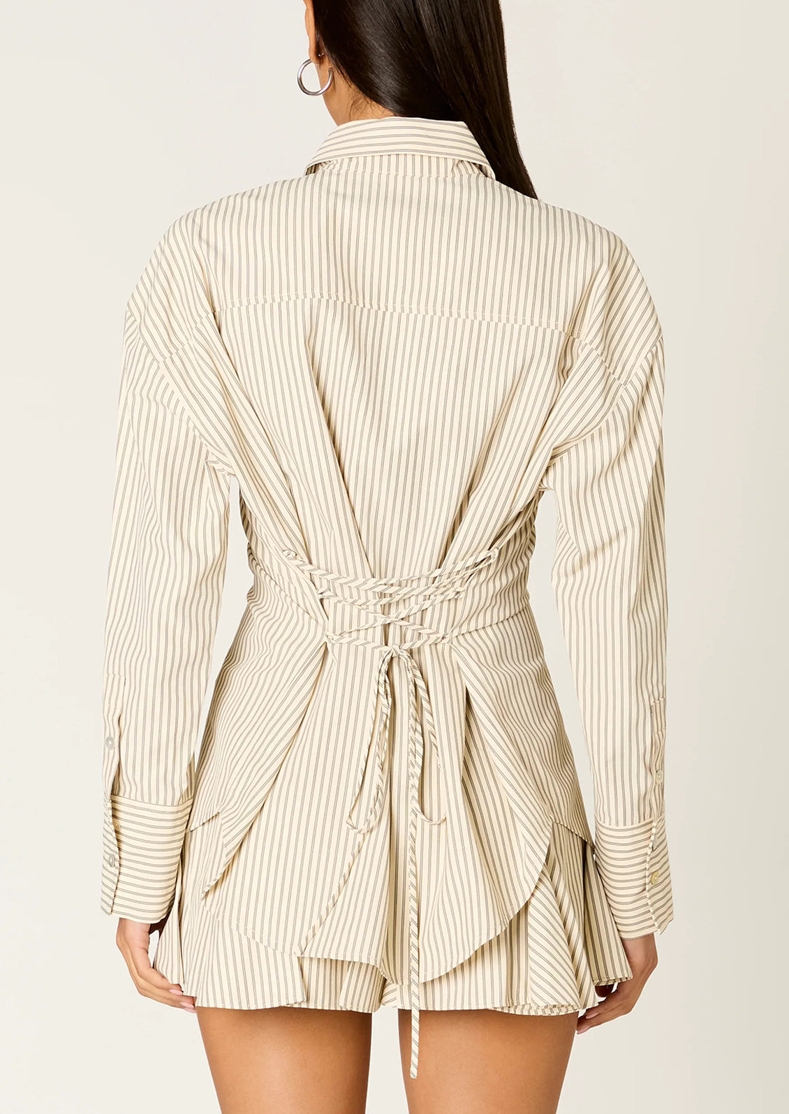 Woman wearing a tan stripe button-up shirt with lace-up back.