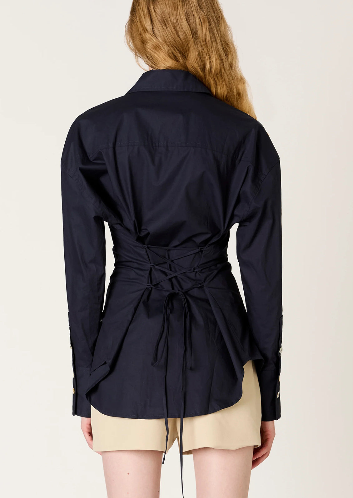 Navy blue jacket with a tie waist worn by a person on a plain background