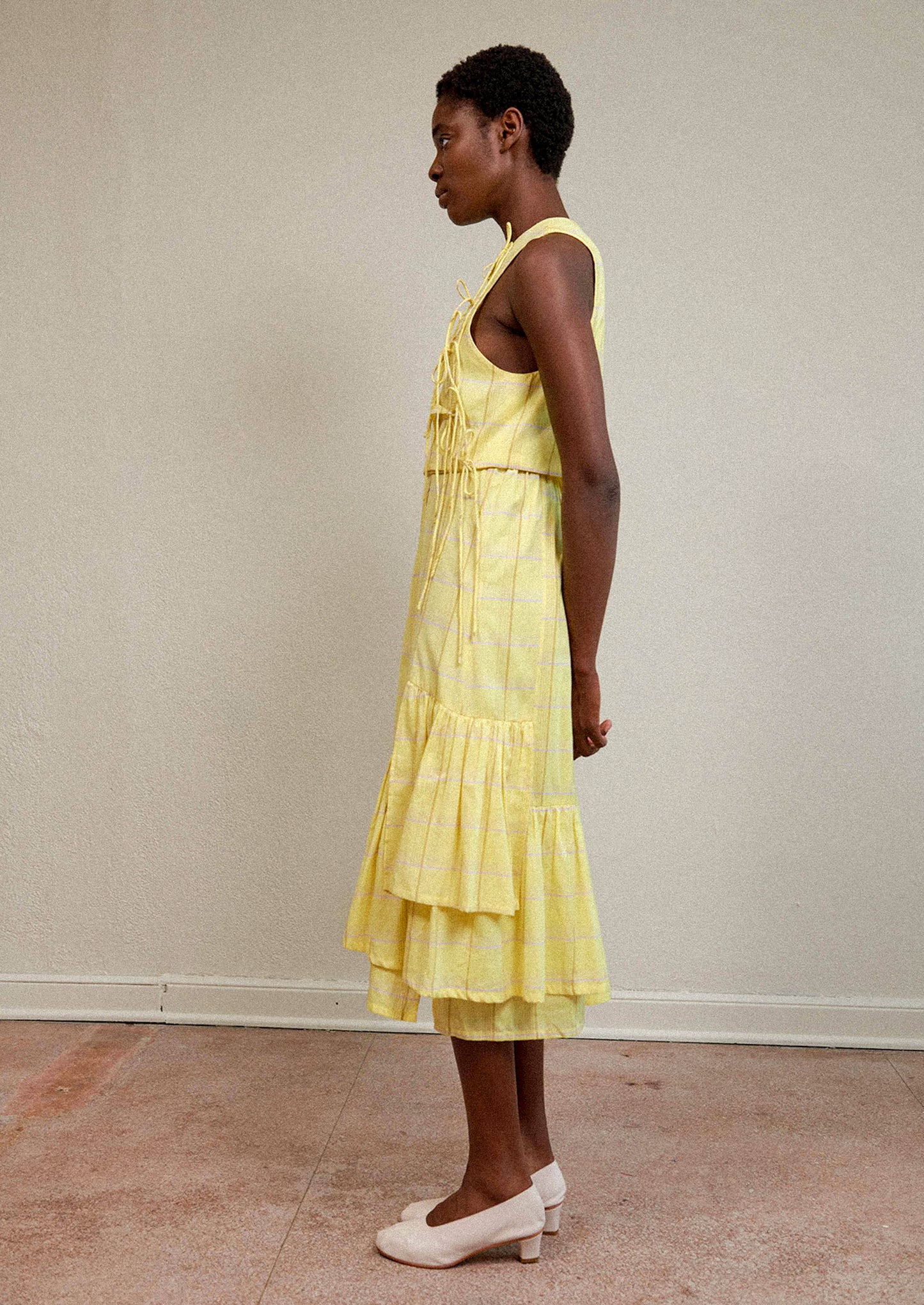 A woman wearing a tie front blouse in yellow plaid fabric.