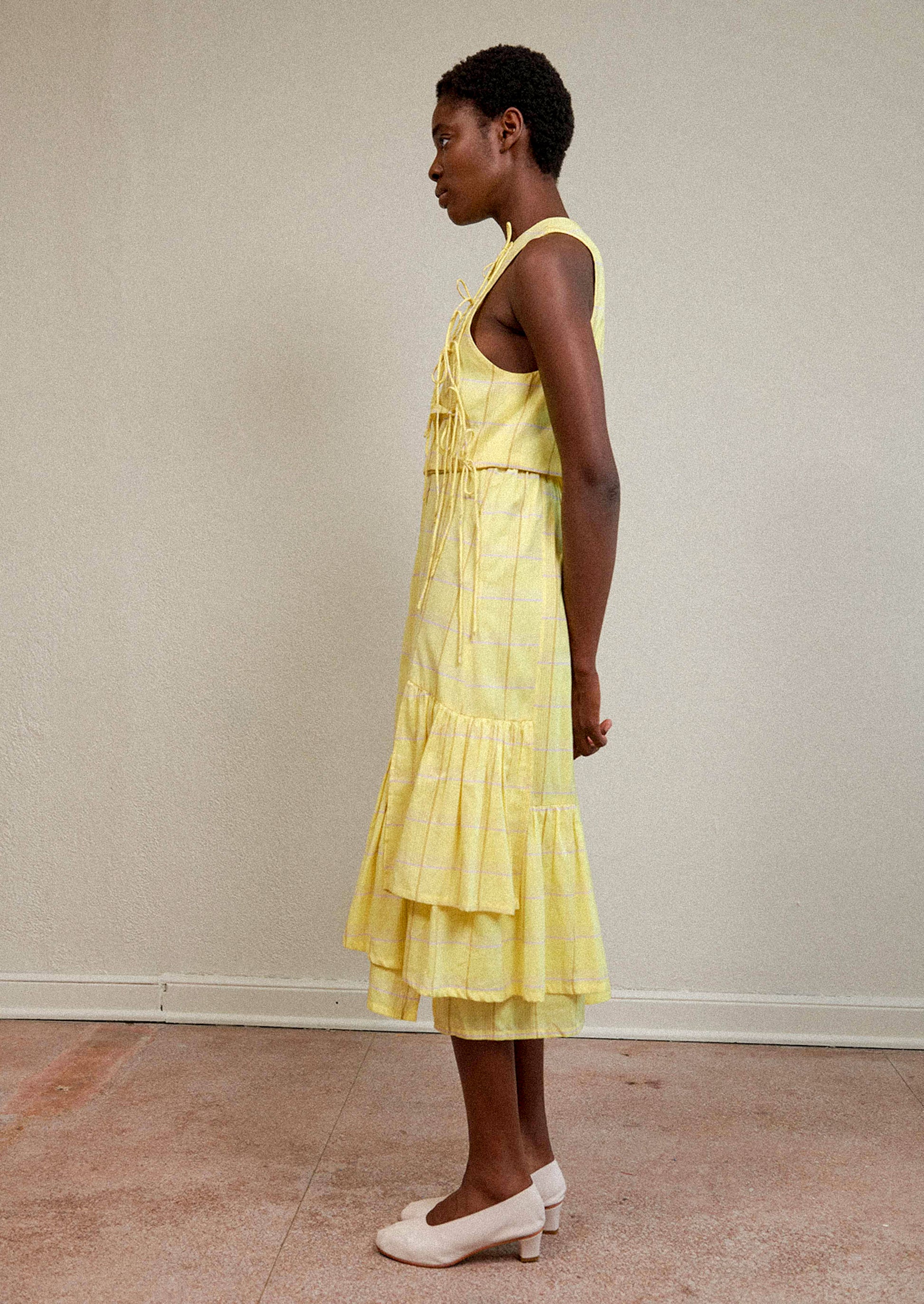 A woman wearing a tie front blouse in yellow plaid fabric.
