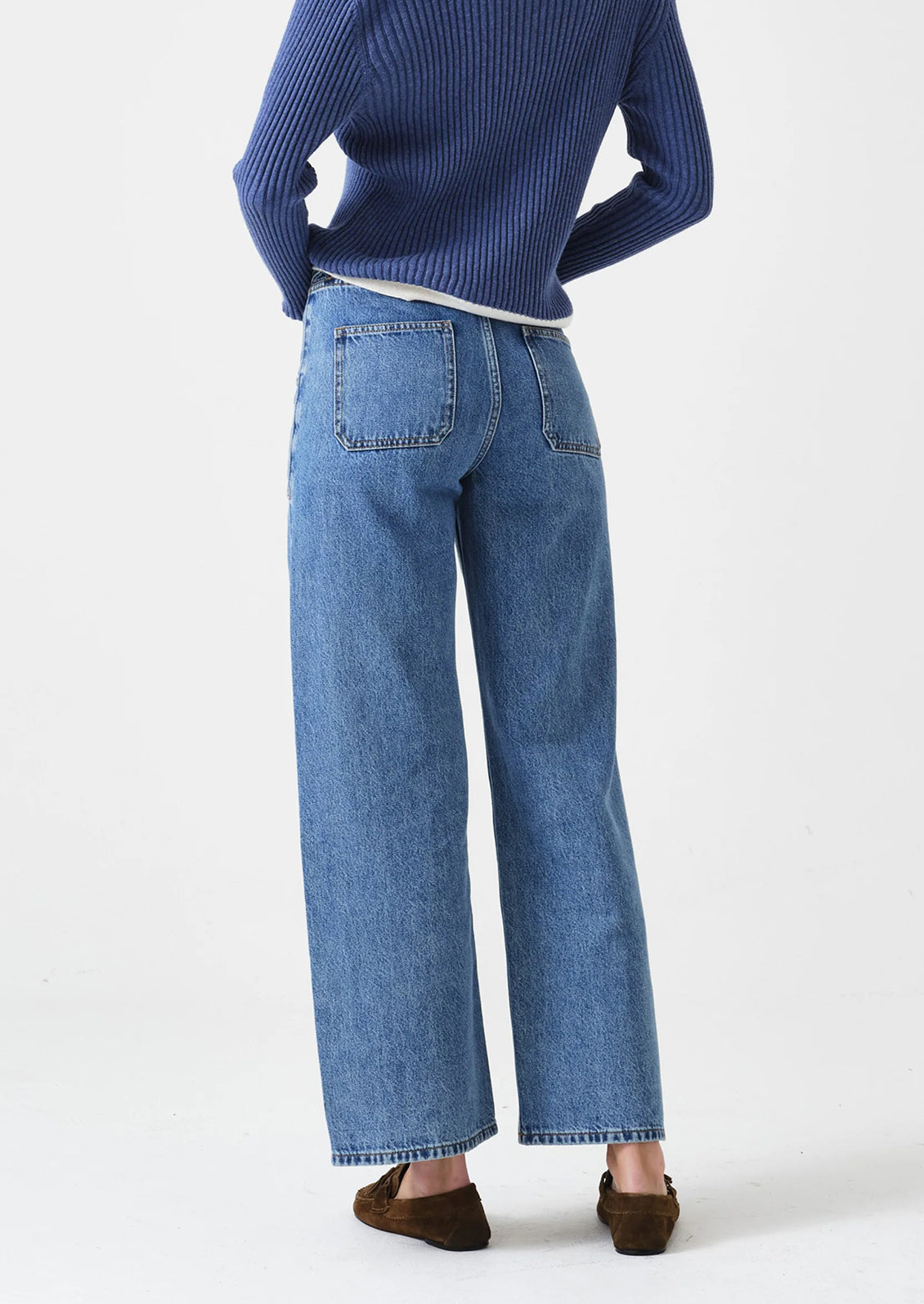 Person wearing blue jeans and a blue sweater on a white background