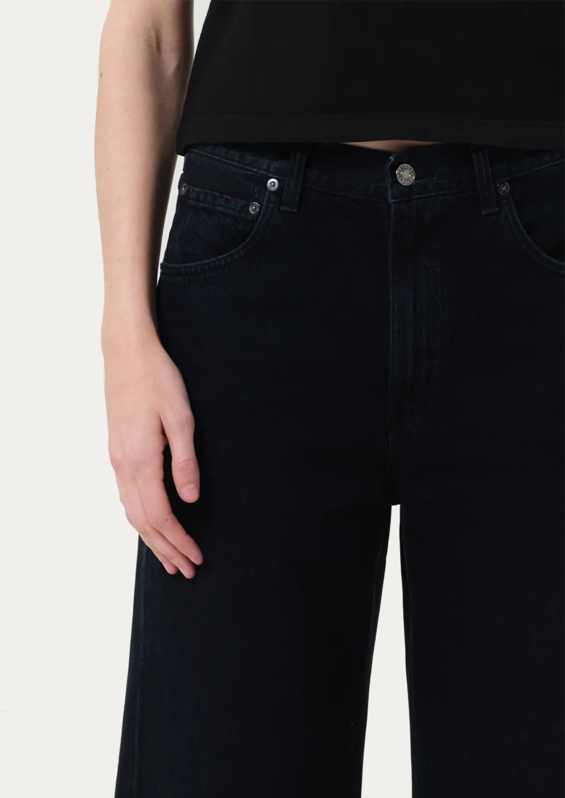 Person wearing black jeans on a plain background