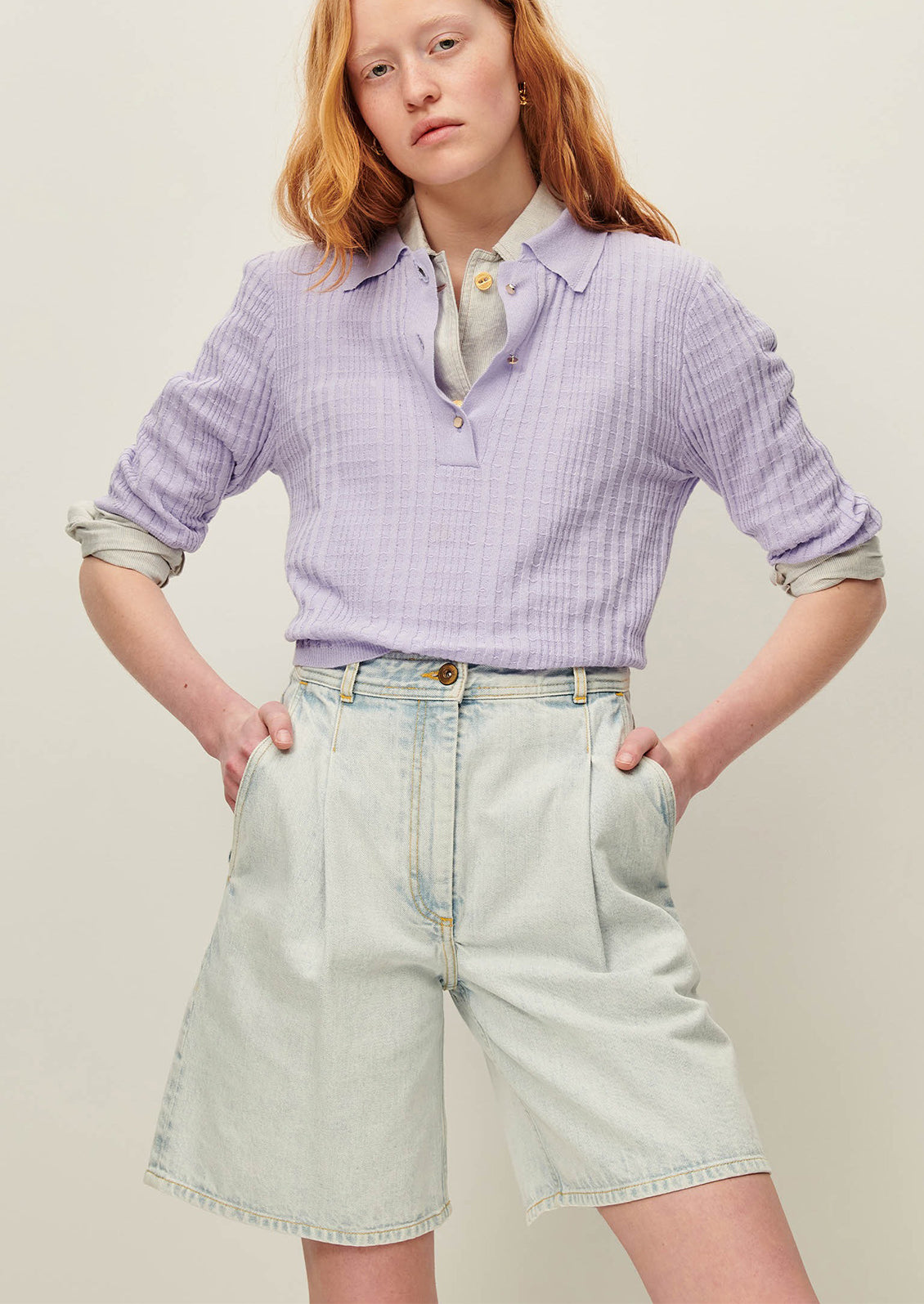 A person wearing a pair of denim bermuda shorts in light blue stonewash.