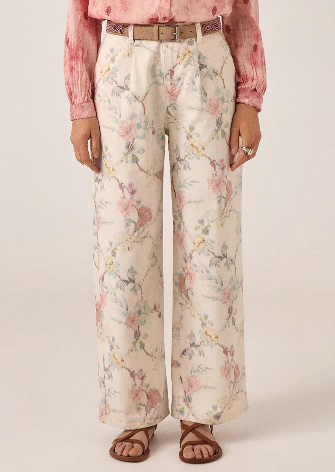 A person wearing a pair of white denim pants with pastel floral print.