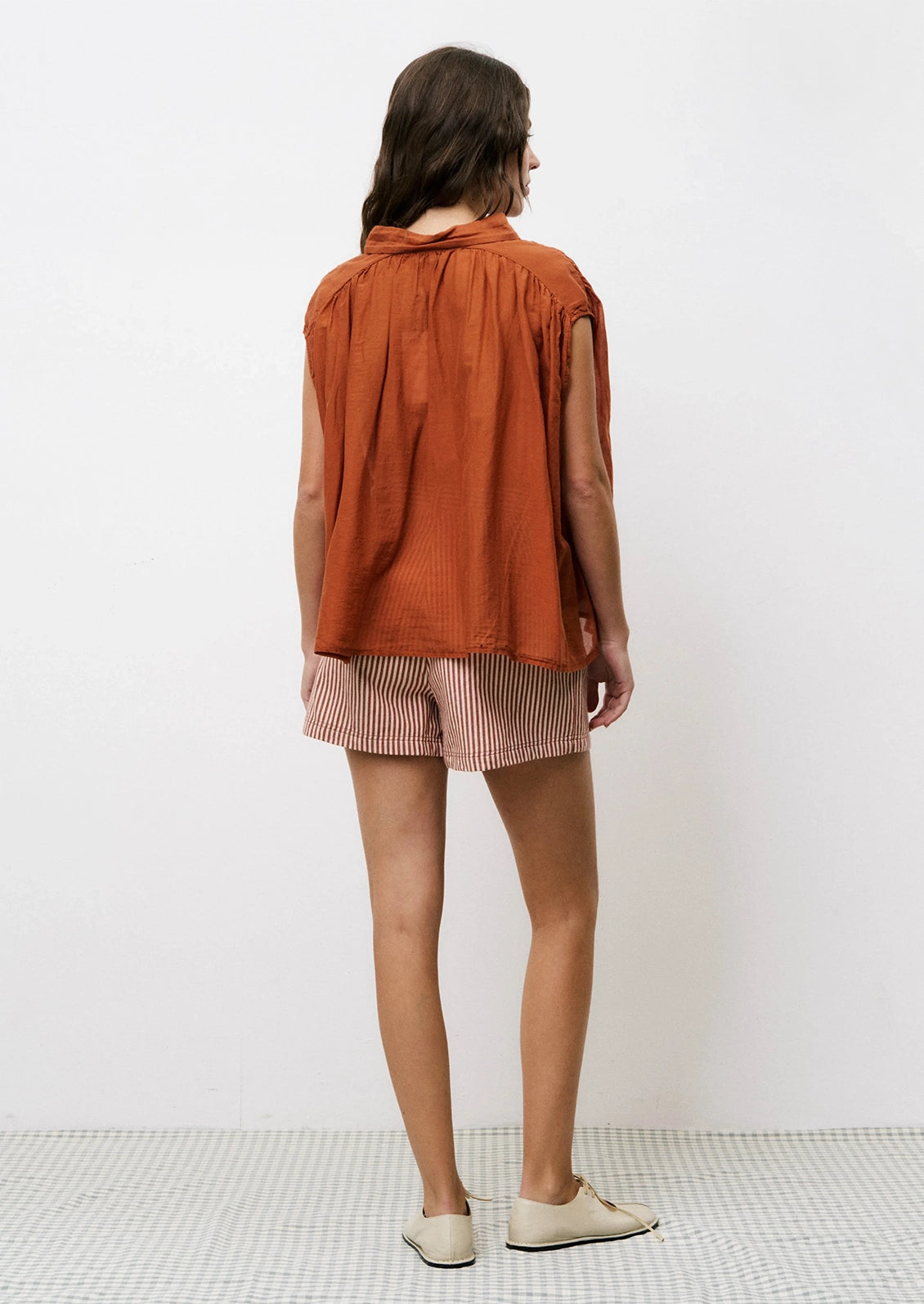 A pair of shorts in cream and rust vertical stripe pattern.