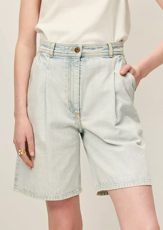 A person wearing a pair of denim bermuda shorts in light blue stonewash.