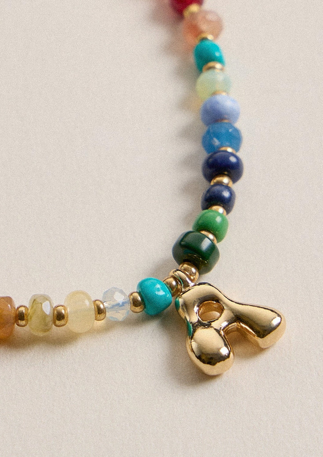 A colorful beaded necklace with a gold A charm.
