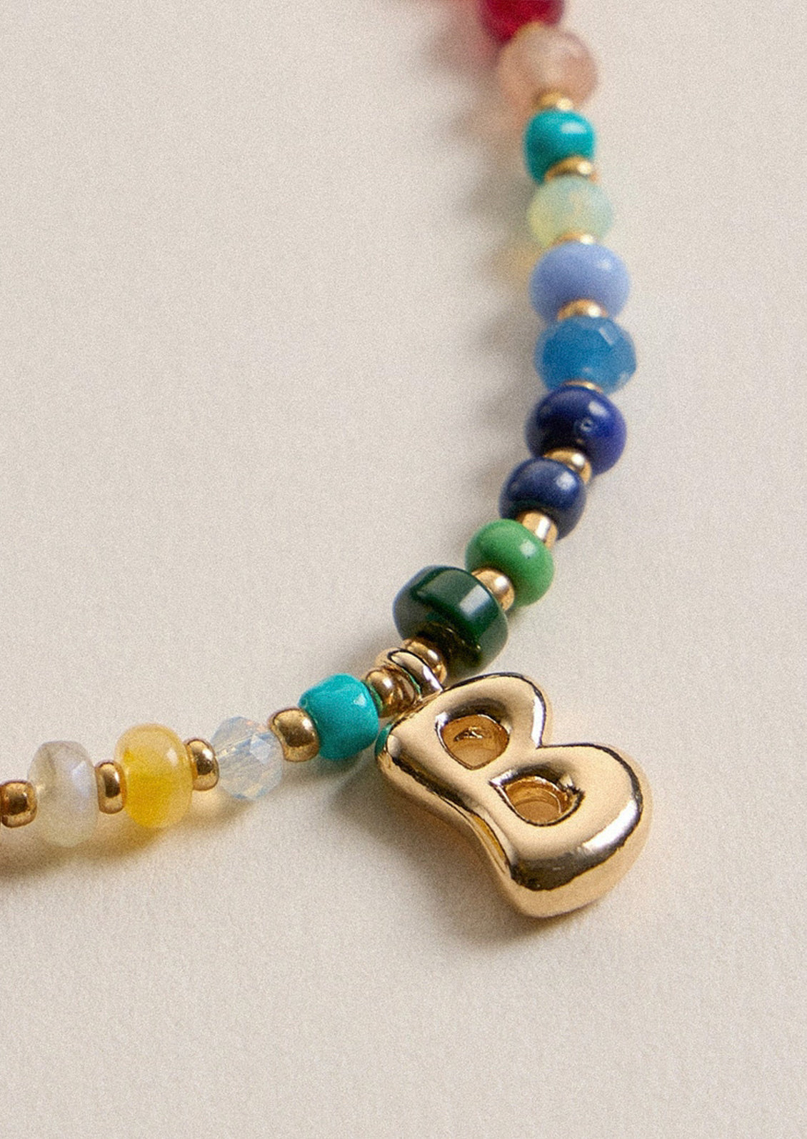 A colorful beaded necklace with a gold B charm.