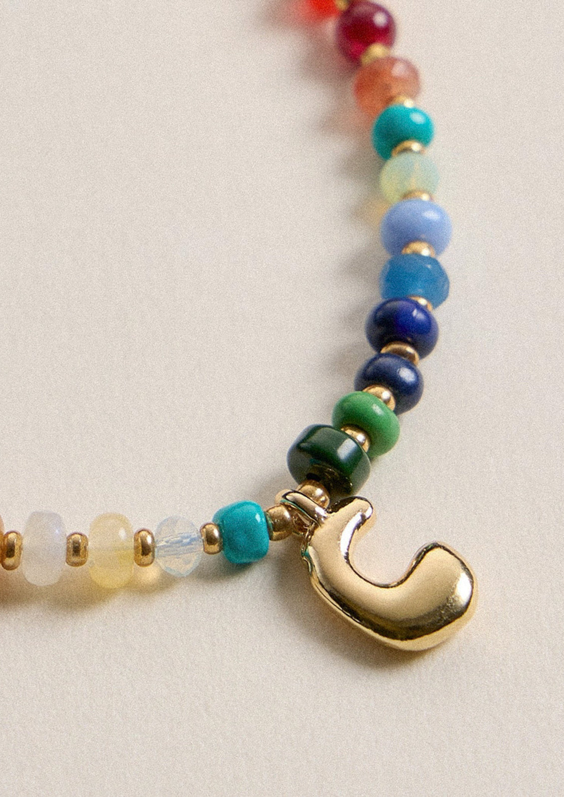 A colorful beaded necklace with a gold C charm.