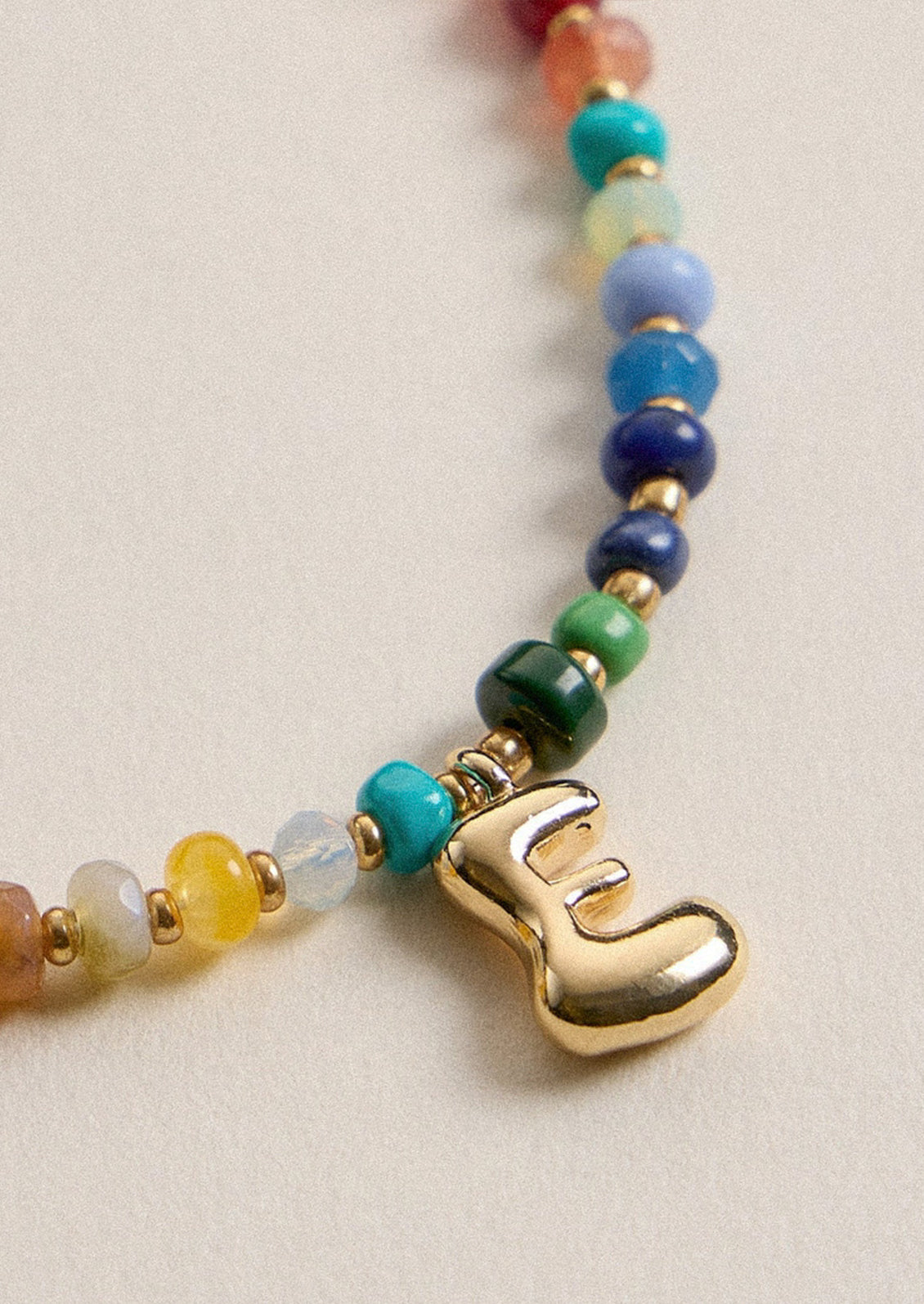 A colorful beaded necklace with a gold E charm.
