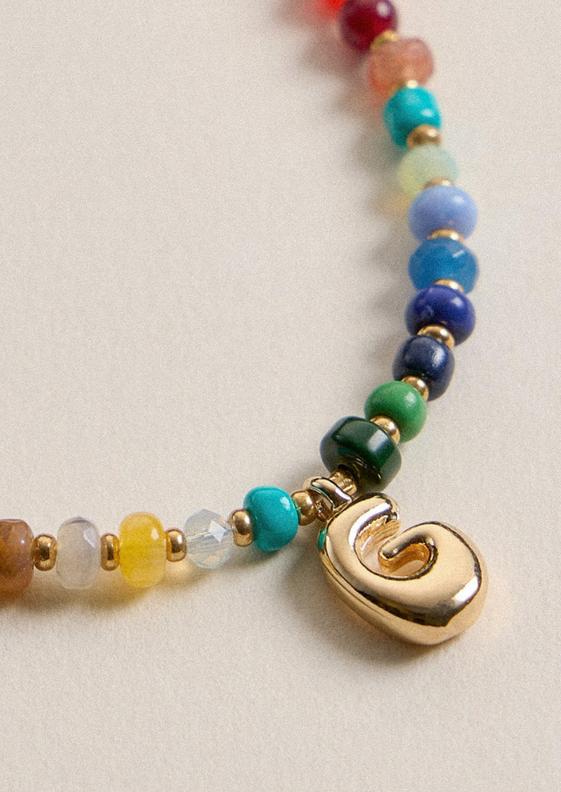 A colorful beaded necklace with a gold G charm.