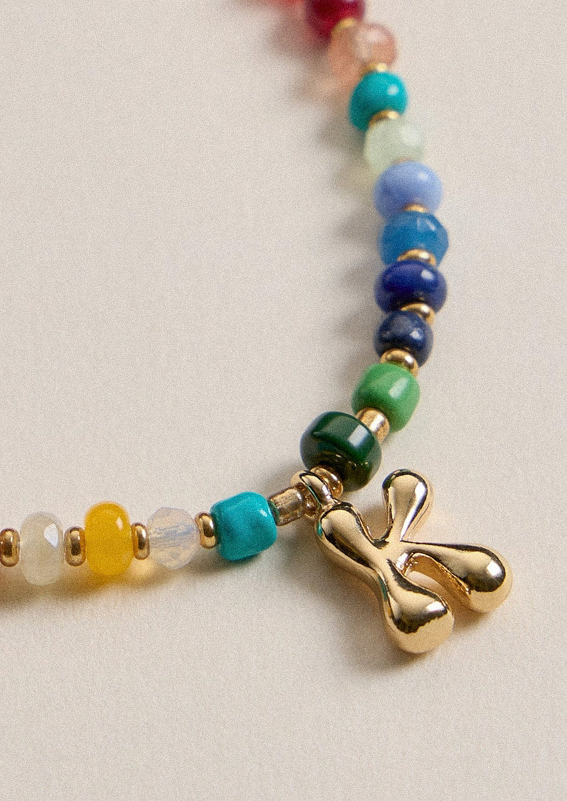 A colorful beaded necklace with a gold K charm.