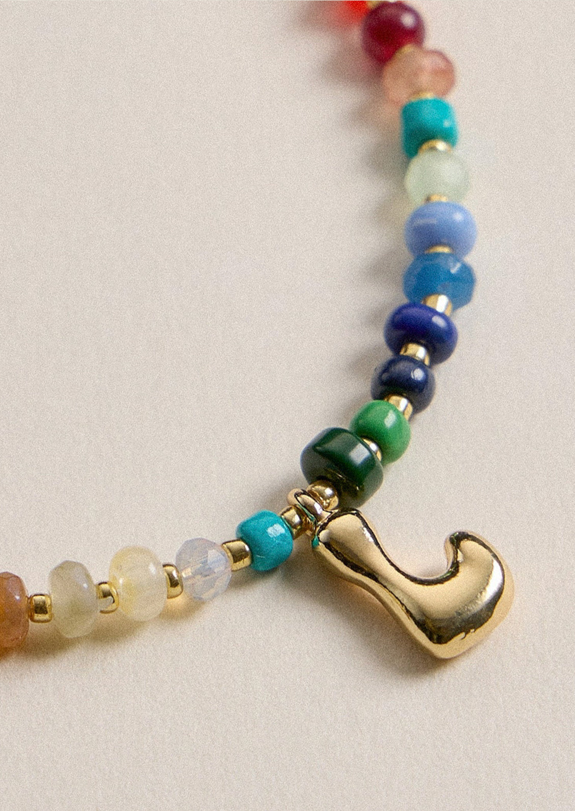 A colorful beaded necklace with a gold L charm.
