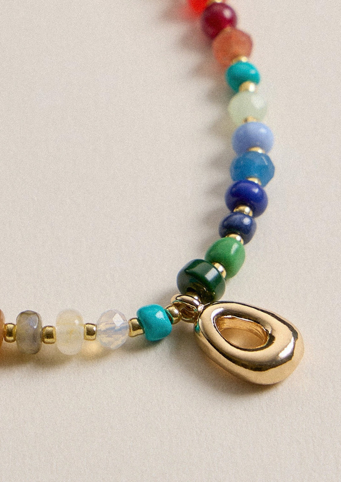 A colorful beaded necklace with a gold O charm.