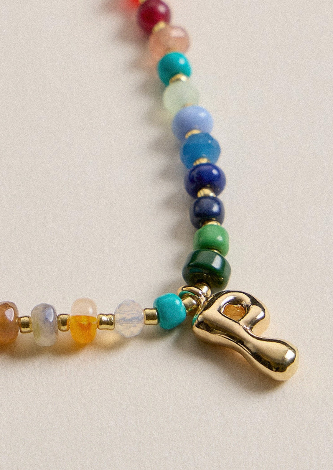 A colorful beaded necklace with a gold P charm.