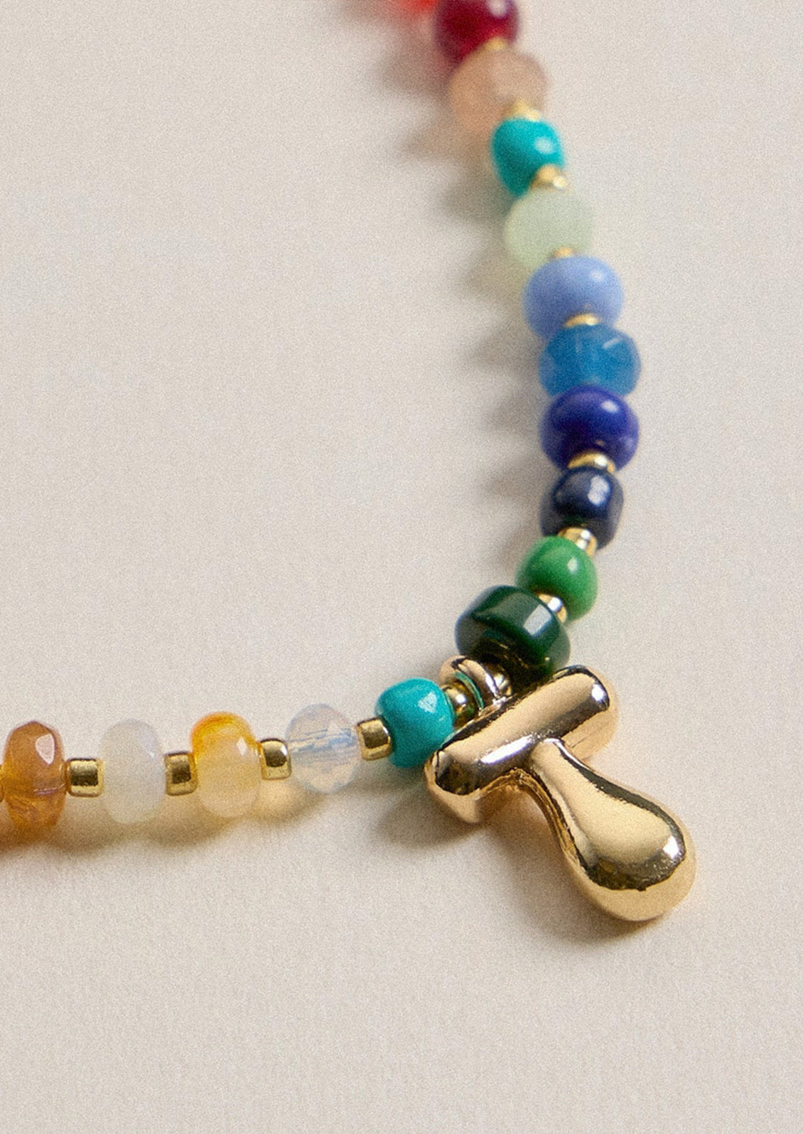 A colorful beaded necklace with a gold T charm.