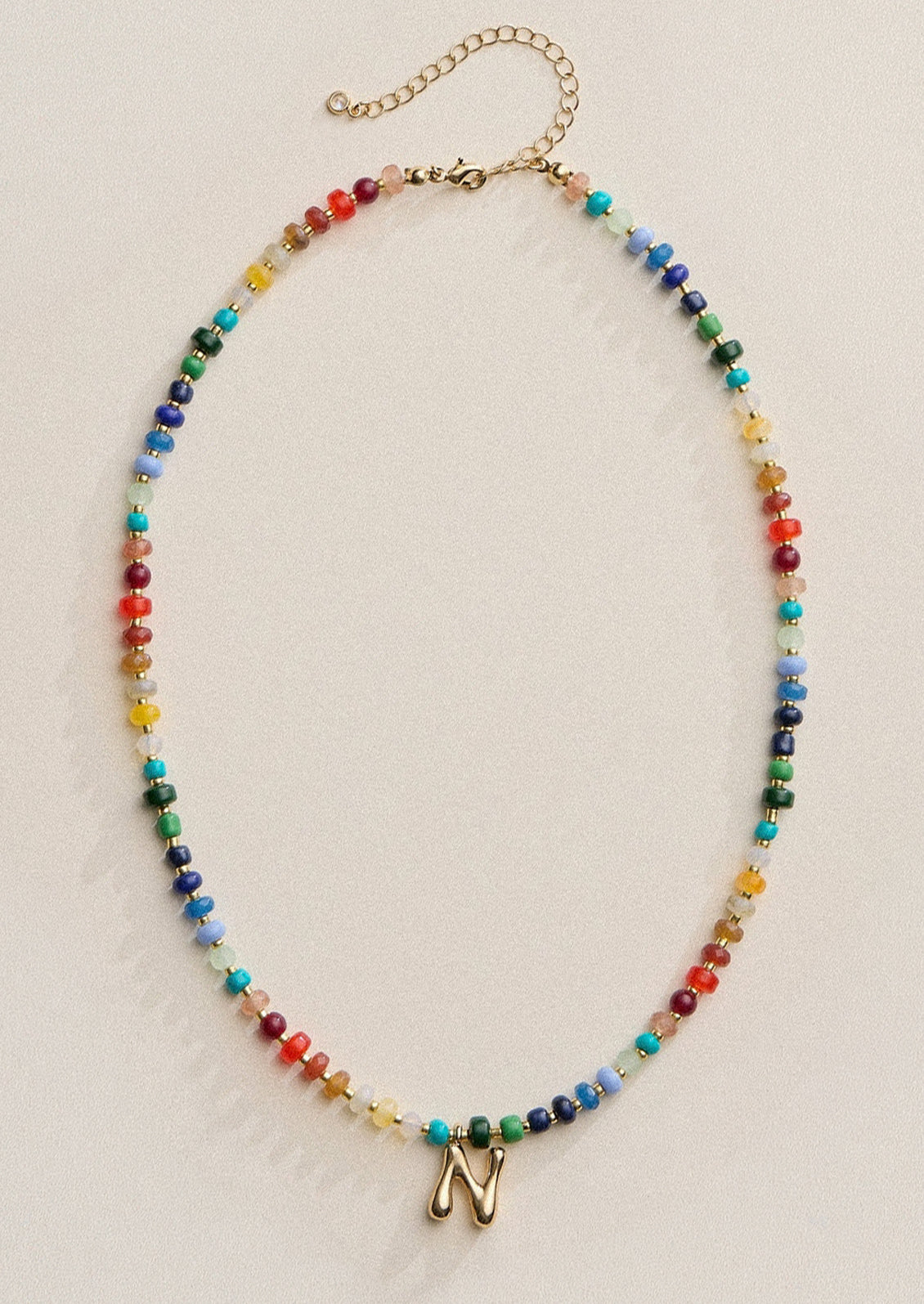 A colorful beaded necklace with a gold N charm.