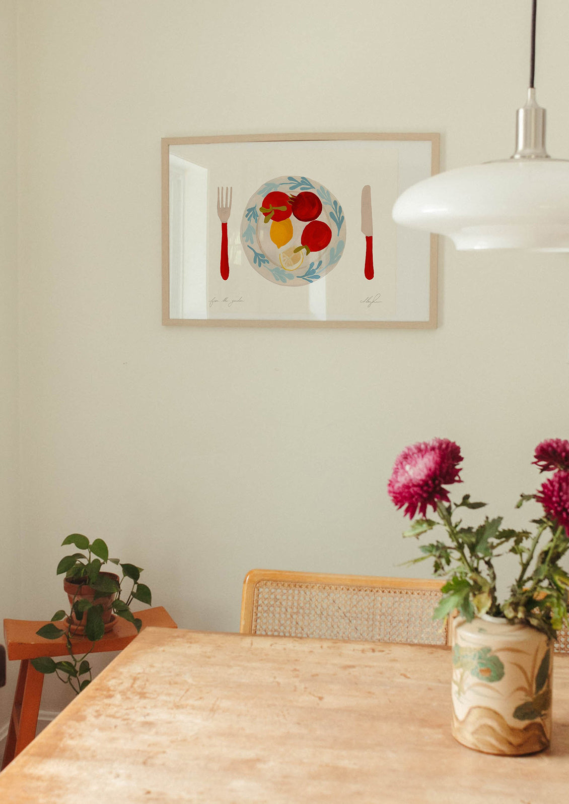 An art print of tomatoes and lemons on a plate with red knife and fork.