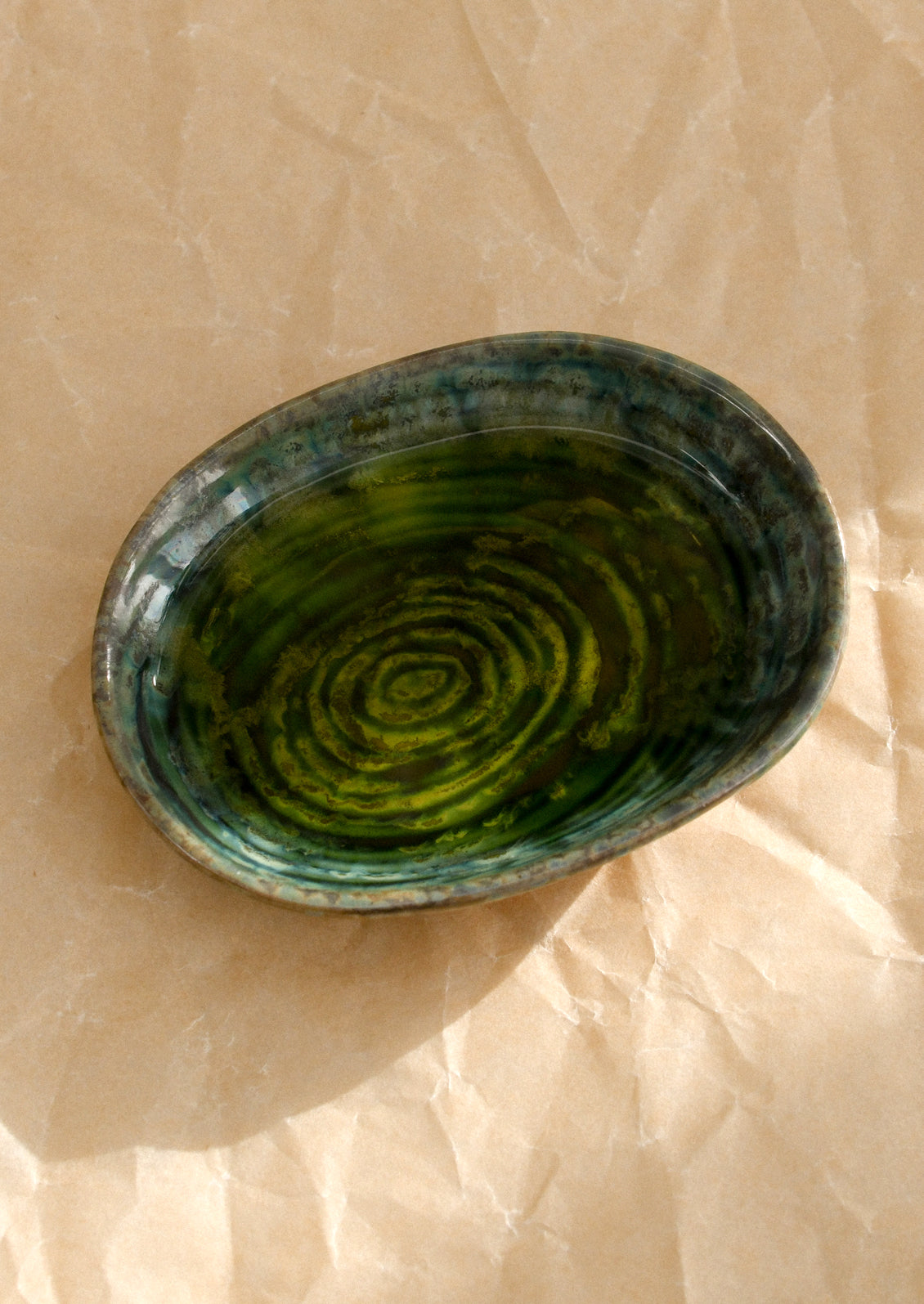 A small ceramic sauce dish in oval shape and deep emerald green reactive glaze.