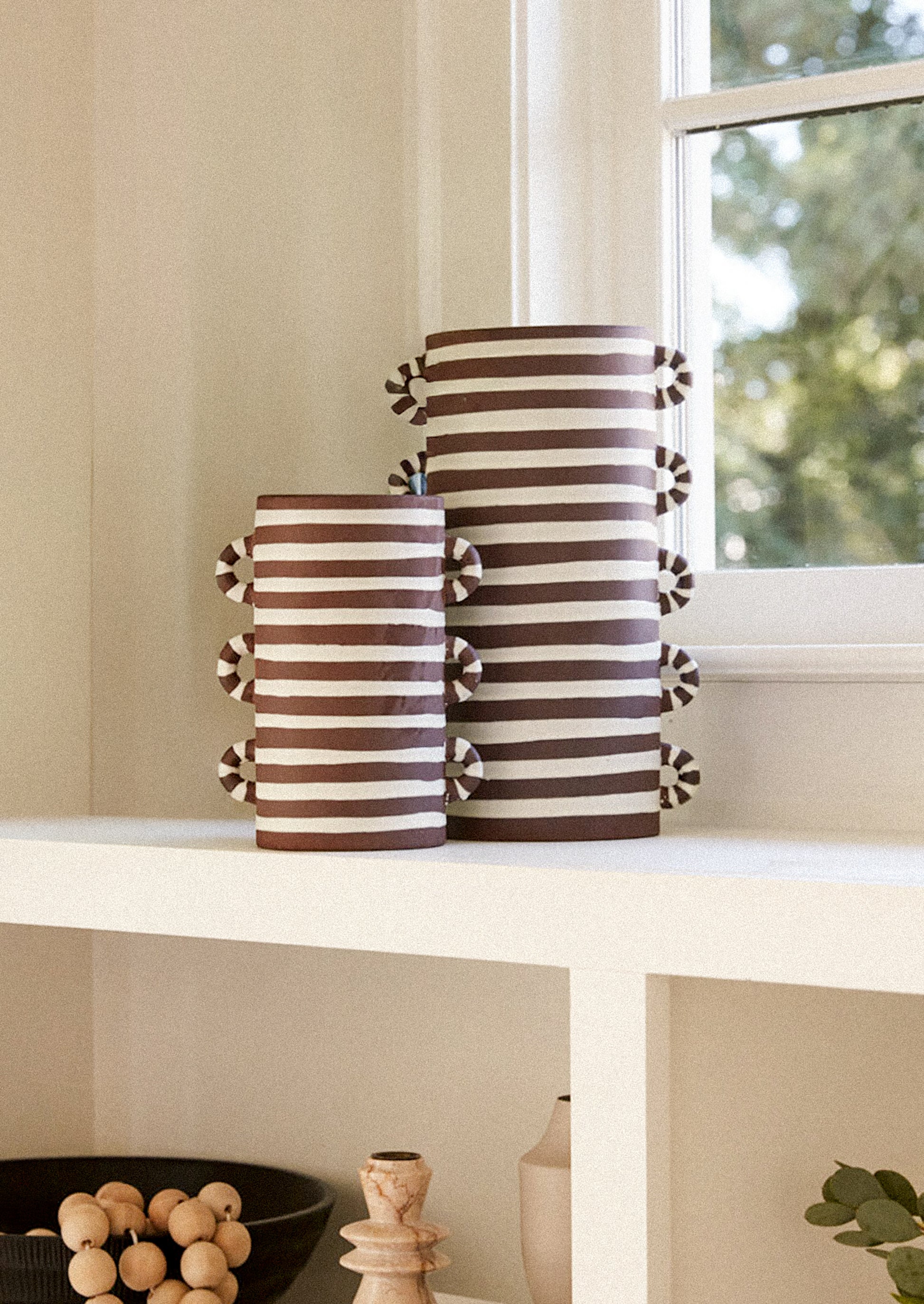 A brown and white ceramic vase with loopy decorative side handles.