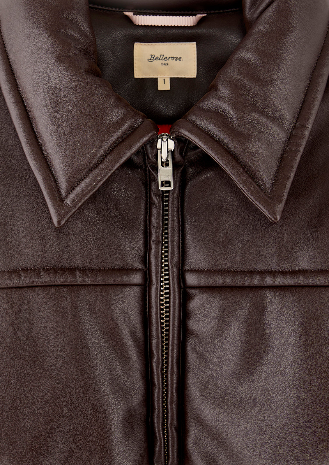 A woman wearing a bomber style jacket in brown faux leather.