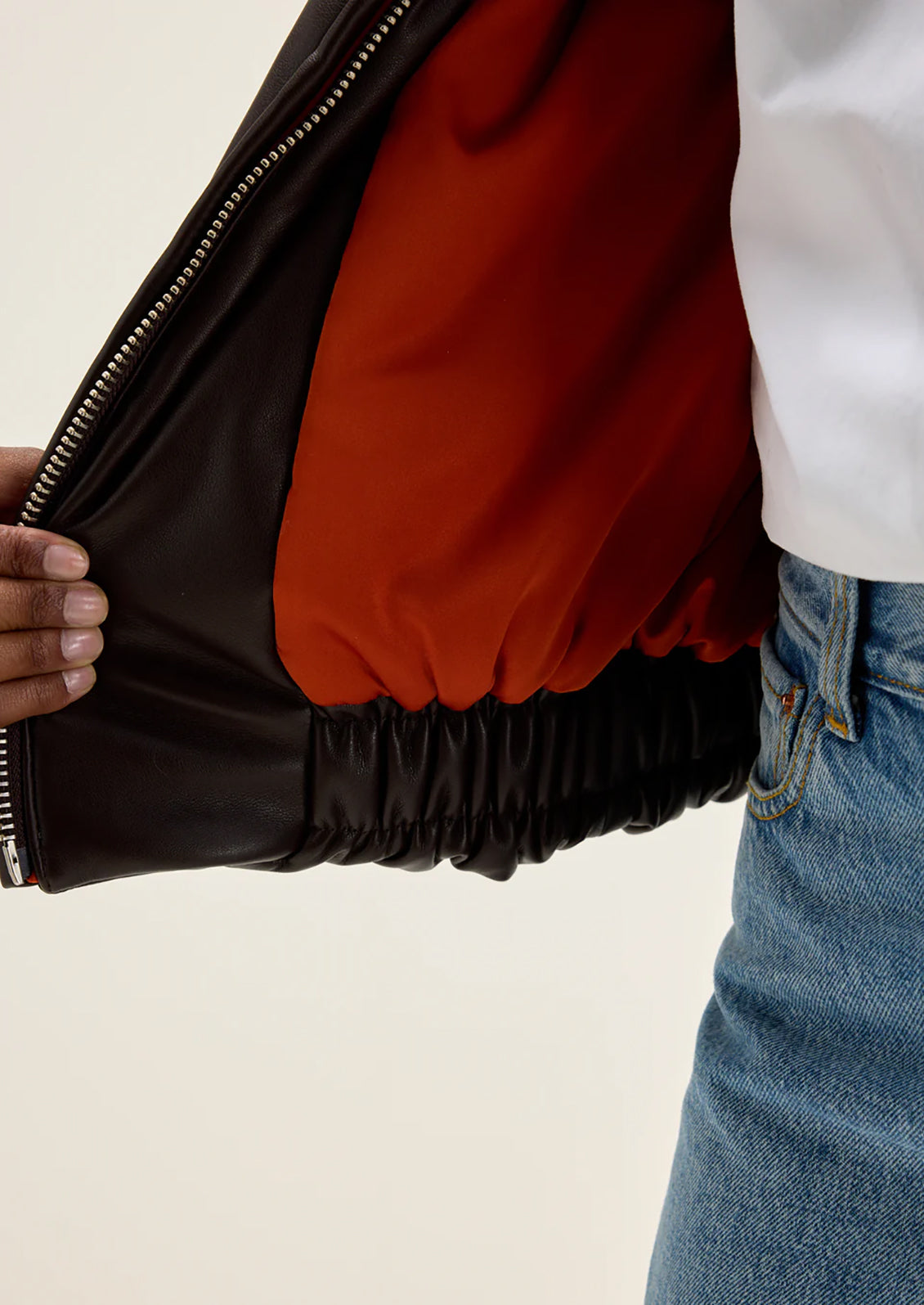 A woman wearing a bomber style jacket in brown faux leather.