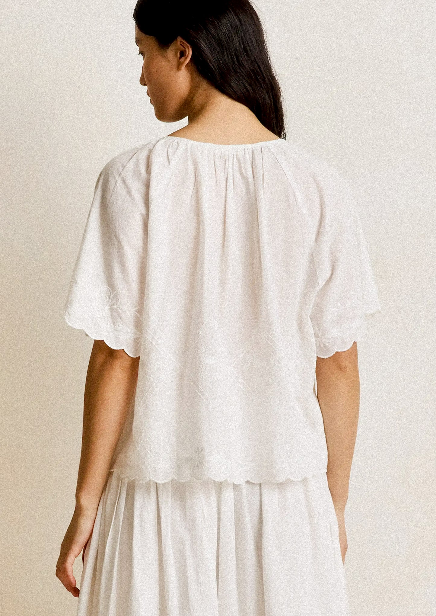 Woman wearing a white blouse with short sleeves on a plain background