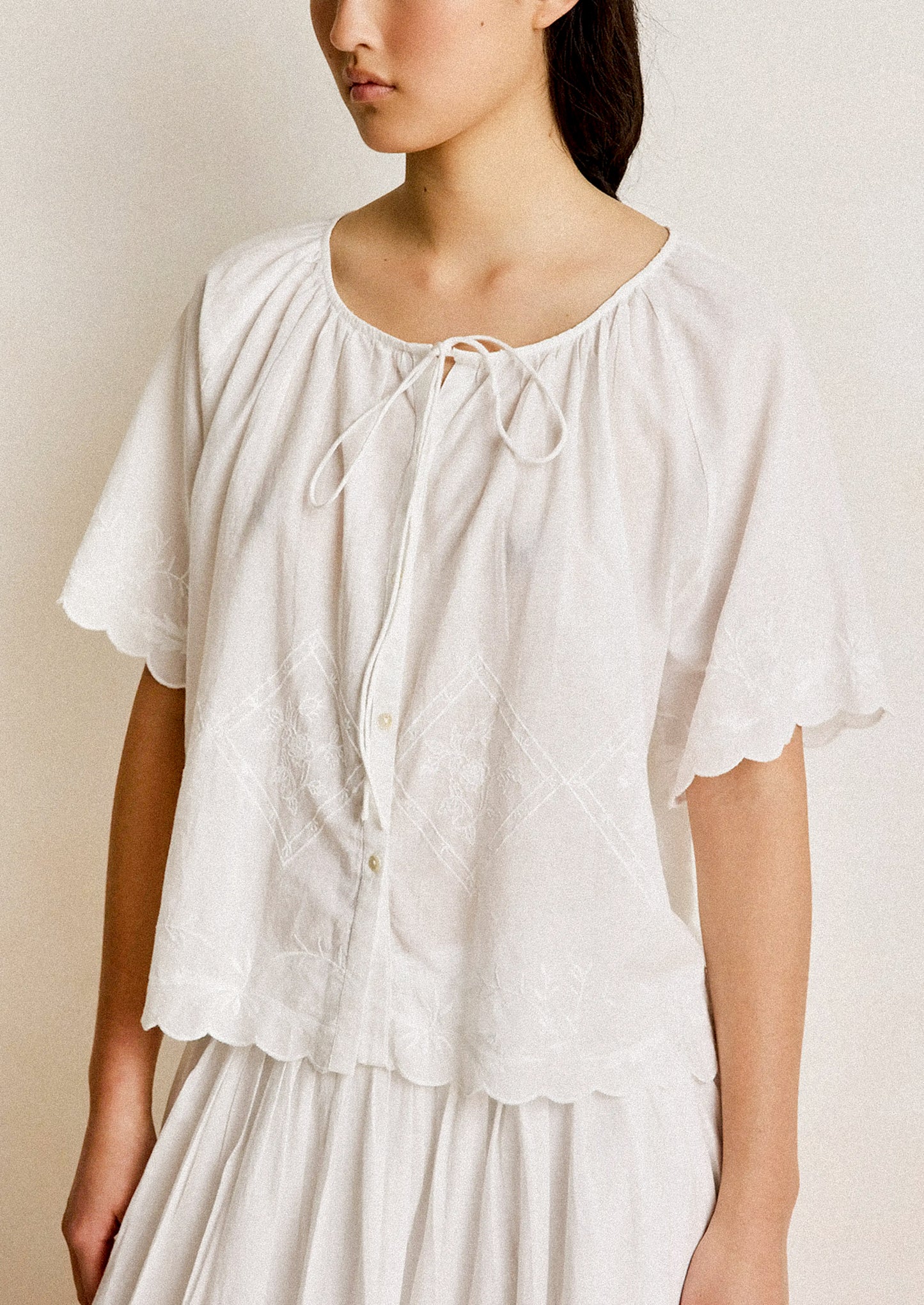 Woman wearing a white blouse with a plain background