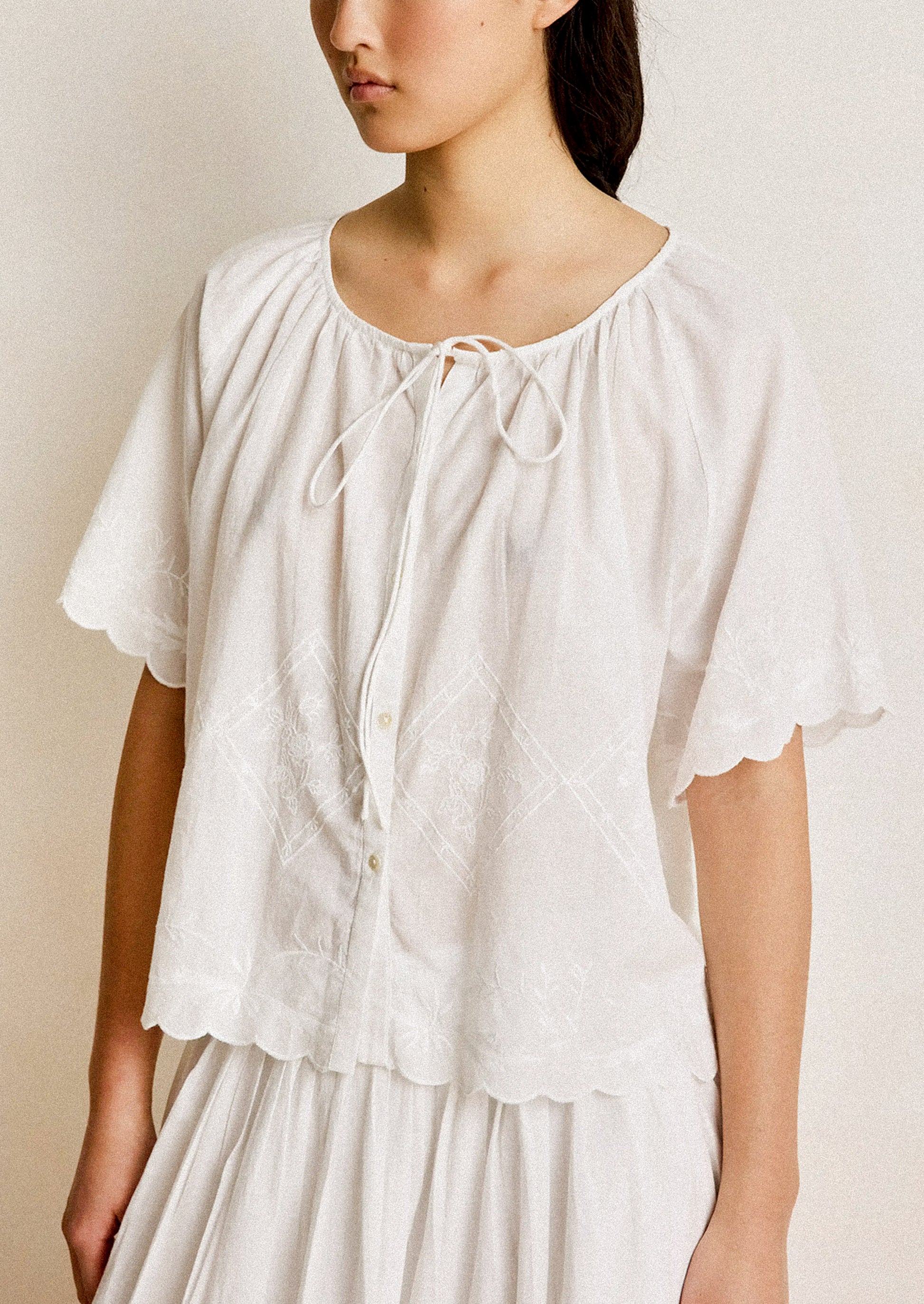 Woman wearing a white blouse with a plain background