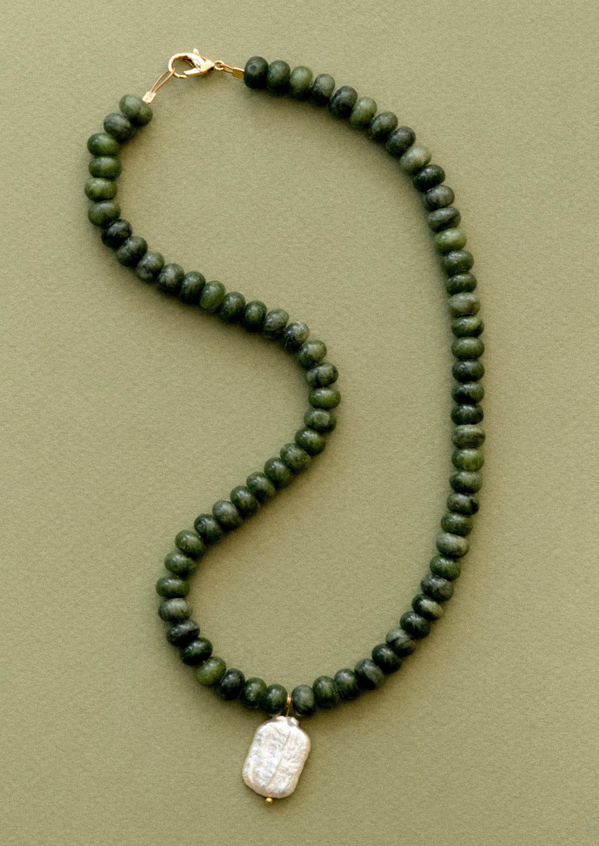 A  necklace with jade beads and pearl pendant.